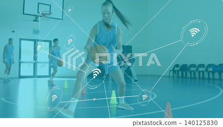 Dribbling player in blue jersey navigating cones in school gym, with balls, hoop, network overlay Dribbling player in blue jersey navigating cones in school gym, with balls, hoop, network overlay 140125830