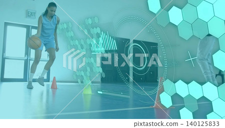 Dribbling female athlete in blue jersey and shorts on blue court, holding basketball near cones Dribbling female athlete in blue jersey and shorts on blue court, holding basketball near cones 140125833