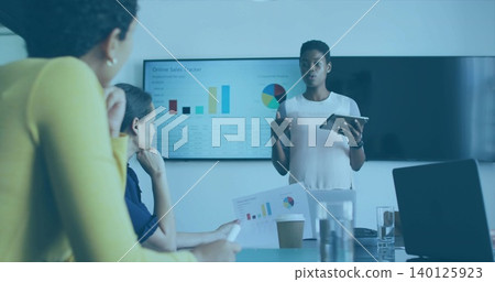 Presenting woman in white top pointing at Online Sales Tracker in conference room, holding tablet Presenting woman in white top pointing at Online Sales Tracker in conference room, holding tablet 140125923