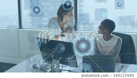 Leaning woman talking while colleague working on laptop at office tower, blazer on chair, AR data Leaning woman talking while colleague working on laptop at office tower, blazer on chair, AR data 140125930