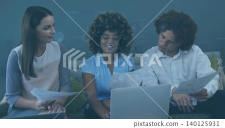 Reviewing three coworkers discussing documents on sofa in office, using laptop wearing work clothes Reviewing three coworkers discussing documents on sofa in office, using laptop wearing work clothes 140125931