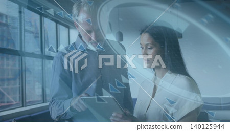 Pointing at tablet, coworkers wearing long-sleeve shirt and light blouse studying HUD in office Pointing at tablet, coworkers wearing long-sleeve shirt and light blouse studying HUD in office 140125944