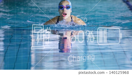 Swimming woman breathing while advancing in lap pool, cap, goggles, one-piece swimsuit overlay Swimming woman breathing while advancing in lap pool, cap, goggles, one-piece swimsuit overlay 140125968