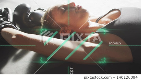 Lying female athlete resting on padded mat at gym, black top, gloves, green HUD numeric readouts Lying female athlete resting on padded mat at gym, black top, gloves, green HUD numeric readouts 140126094
