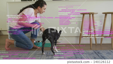 Kneeling woman pink top, jeans reaching to black dog in kitchen with steel bowl, purple-pink code Kneeling woman pink top, jeans reaching to black dog in kitchen with steel bowl, purple-pink code 140126112