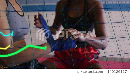 Wrapping two female athletes' hands in boxing gym, with blue wrap, sports bras, red shorts, HUD Wrapping two female athletes' hands in boxing gym, with blue wrap, sports bras, red shorts, HUD 140126117
