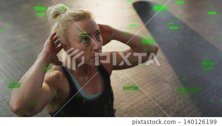 Doing crunch, fit woman with hands-behind-head on rubber floor with green overlay in athletic wear 140126199