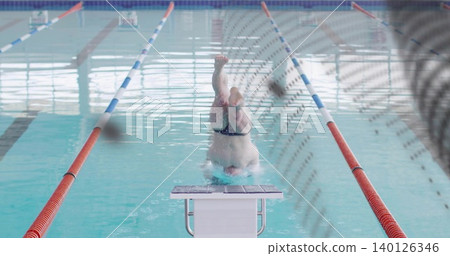 Diving male swimmer wearing dark briefs entering water at pool starting block, with lane ropes Diving male swimmer wearing dark briefs entering water at pool starting block, with lane ropes 140126346