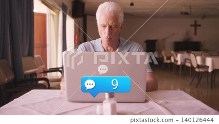 Working senior man wearing light blue polo typing on laptop in church hall with chat-9 Working senior man wearing light blue polo typing on laptop in church hall with chat-9 140126444