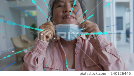 Grasping ear loops, Korean man pulling blue mask beneath chin in lobby, pink shirt, teal splatter Grasping ear loops, Korean man pulling blue mask beneath chin in lobby, pink shirt, teal splatter 140126446