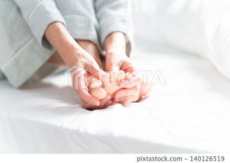 A woman wakes up in bed with cramps in her legs 140126519