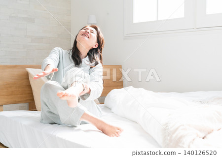 A woman wakes up in bed with cramps in her legs A woman wakes up in bed with cramps in her legs 140126520