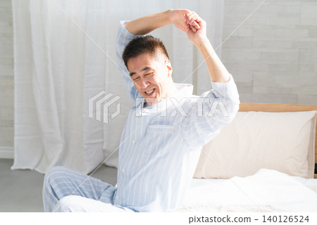 A man wakes up and stretches on his bed A man wakes up and stretches on his bed 140126524