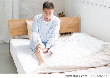 一名男子在床上醒來,雙腿抽筋 一名男子在床上醒來,雙腿抽筋 140126534