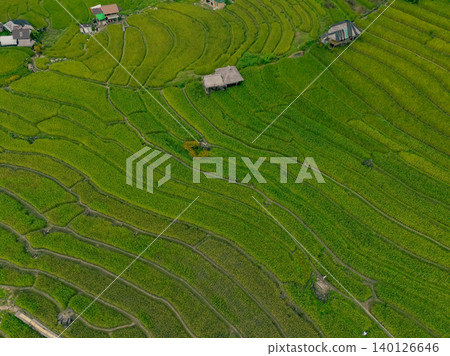 Aerial view of lush green rice terraces in mountain with patterns and small rural homes. Sustainable farming and eco tourism in Asia. Organic agriculture and homestays promoting rural development. Aerial view of lush green rice terraces in mountain with patterns and small rural homes. Sustainable farming and eco tourism in Asia. Organic agriculture and homestays promoting rural development. 140126646