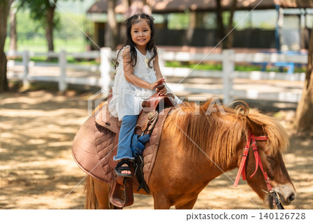 happy toddler girl riding the brown horse 140126728