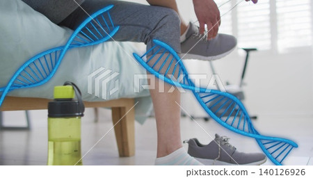 Tying woman wearing gray leggings lacing gray shoe in bedroom, with lime green bottle, bike, DNA Tying woman wearing gray leggings lacing gray shoe in bedroom, with lime green bottle, bike, DNA 140126926