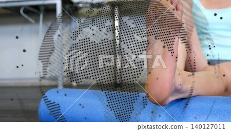 Resting woman in blue top placing bare feet on blue-foam roller in gym, dotted-panel, copy space Resting woman in blue top placing bare feet on blue-foam roller in gym, dotted-panel, copy space 140127011