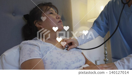 Leaning nurse placing stethoscope on patient wearing floral gown at bedside, heart overlays Leaning nurse placing stethoscope on patient wearing floral gown at bedside, heart overlays 140127014