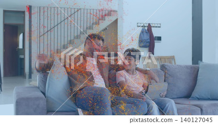 Smiling father and son sitting on sofa at home near stairs, father brown-jacket, son holding tablet Smiling father and son sitting on sofa at home near stairs, father brown-jacket, son holding tablet 140127045