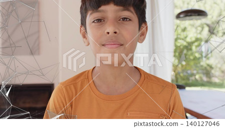 Standing Indian boy facing camera in living dining area, wearing orange T-shirt near pendant lamp Standing Indian boy facing camera in living dining area, wearing orange T-shirt near pendant lamp 140127046