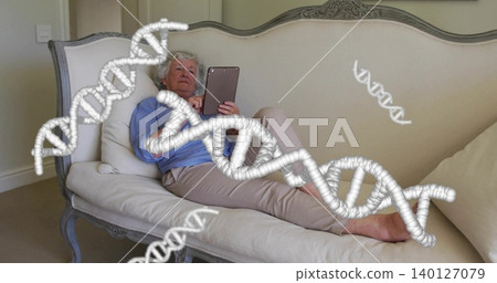 Reclining senior woman using tablet on antique sofa at home while viewing DNA overlays, barefoot Reclining senior woman using tablet on antique sofa at home while viewing DNA overlays, barefoot 140127079