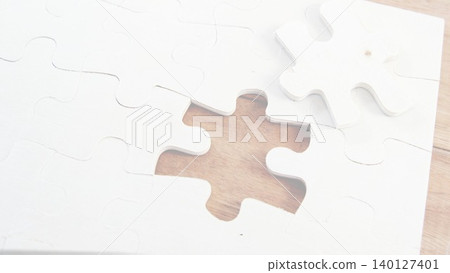 white jigsaw puzzle is showing missing piece on wooden tabletop, flat design for business strategy white jigsaw puzzle is showing missing piece on wooden tabletop, flat design for business strategy 140127401