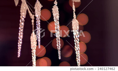 Crystal icicle ornaments are hanging in flat design holiday decor scene, with warm bokeh lights Crystal icicle ornaments are hanging in flat design holiday decor scene, with warm bokeh lights 140127462