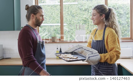 Couple is baking cookies in flat design kitchen illustration, food theme with tray and oven mitts Couple is baking cookies in flat design kitchen illustration, food theme with tray and oven mitts 140127463