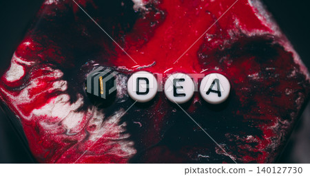 Idea word. Glitter paint rhombus. Defocused red white color rock geometric black letters texture on abstract creative art background. Idea word. Glitter paint rhombus. Defocused red white color rock geometric black letters texture on abstract creative art background. 140127730