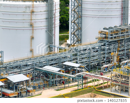 Industrial oil refinery with complex network of steel pipelines and massive storage tanks. Petrochemical plant producing fuel energy. Modern industrial infrastructure for petroleum processing. Industrial oil refinery with complex network of steel pipelines and massive storage tanks. Petrochemical plant producing fuel energy. Modern industrial infrastructure for petroleum processing. 140127835