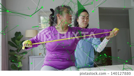 Stretching patient in purple top gray pants on sofa at home, medical therapist guiding yellow band Stretching patient in purple top gray pants on sofa at home, medical therapist guiding yellow band 140127880