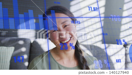 Smiling woman sitting on gray sofa in living room, with blue data overlays and blinds shadows Smiling woman sitting on gray sofa in living room, with blue data overlays and blinds shadows 140127940