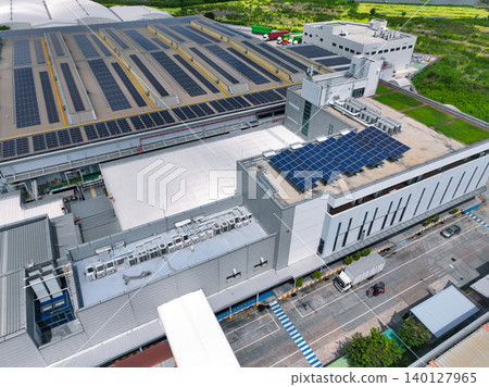 Solar-powered warehouse facility with freight trucks at loading docks. Eco-friendly logistics and efficient cargo transportation. Solar panels and sustainable energy concept in distribution center. 140127965