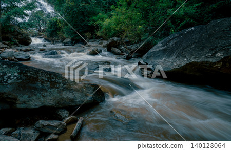 Beautiful waterfall with a lush green forest in the background. The water is flowing down the rocks and creating a beautiful scene. Sustainable waterfall in lush forest promoting water sustainability. 140128064