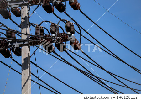 Modern electrical power infrastructure detail showing high voltage transmission lines and ceramic insulators against clear blue sky demonstrating energy distribution. Industrial power grid equipment. Modern electrical power infrastructure detail showing high voltage transmission lines and ceramic insulators against clear blue sky demonstrating energy distribution. Industrial power grid equipment. 140128112