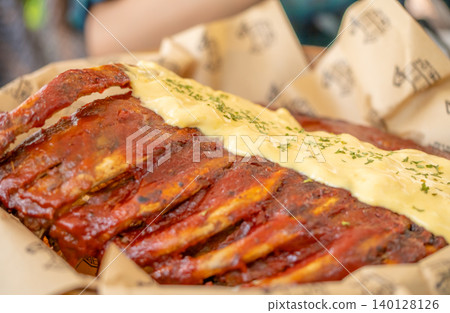 A rack of ribs with a creamy sauce on top. The ribs are cooked and appear to be very tender. The sauce is a creamy white sauce that complements the meat well. Concept of indulgence and satisfaction 140128126