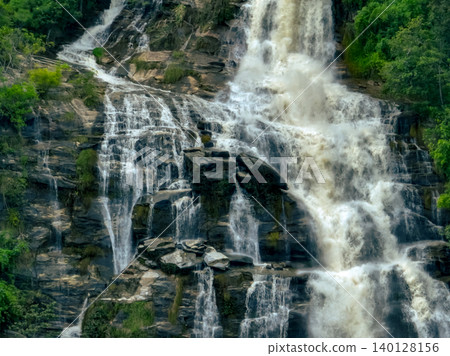 Aerial view of a waterfall in a lush tropical green forest in Doi Inthanon National Park, Chiang Mai, Thailand. This nature landscape showcases water sustainability and scenic travel destinations. Aerial view of a waterfall in a lush tropical green forest in Doi Inthanon National Park, Chiang Mai, Thailand. This nature landscape showcases water sustainability and scenic travel destinations. 140128156