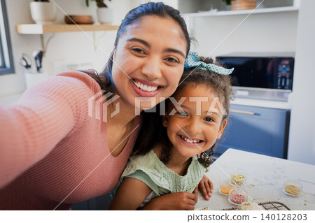 Mother and daughter taking selfie with phone at kitchen table decorating cookies with sprinkles Mother and daughter taking selfie with phone at kitchen table decorating cookies with sprinkles 140128203