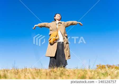 Woman stretching her arms on top of a hill lifestyle image Woman stretching her arms on top of a hill lifestyle image 140128757