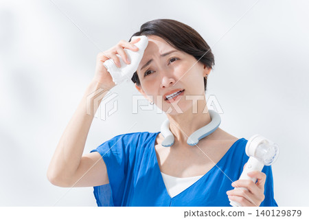 A woman using an ice ring and a handheld fan in the summer. A woman using an ice ring and a handheld fan in the summer. 140129879