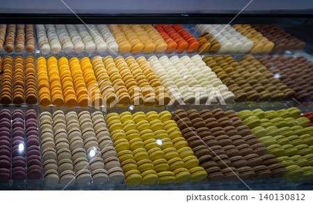 A vibrant display of macarons in various colors, arranged neatly in trays, highlighting their smooth textures and appealing designs, perfect for French dessert lovers 140130812