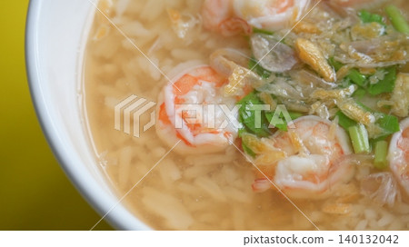 rice soup with shrimp in white bowl on yellow background 140132042