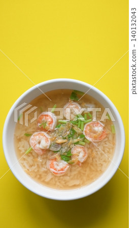 rice soup with shrimp in white bowl on yellow background rice soup with shrimp in white bowl on yellow background 140132043
