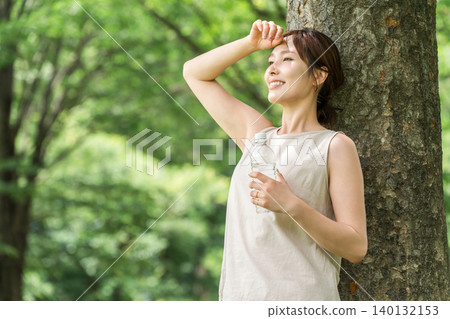 一位婦女在森林裡喝水(補充水分,礦泉水,鈉) 一位婦女在森林裡喝水(補充水分,礦泉水,鈉) 140132153