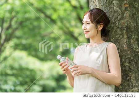 一位神態輕鬆的女士正在喝瓶裝水、礦泉水和熱水。 一位神態輕鬆的女士正在喝瓶裝水、礦泉水和熱水。 140132155