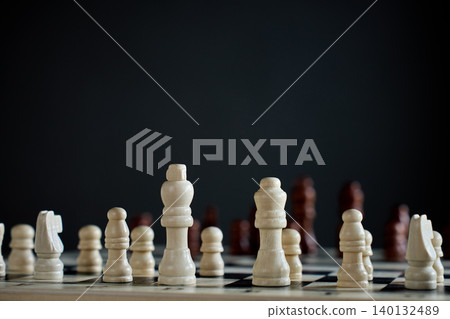 White chess pieces on board against dark background White chess pieces on board against dark background 140132489