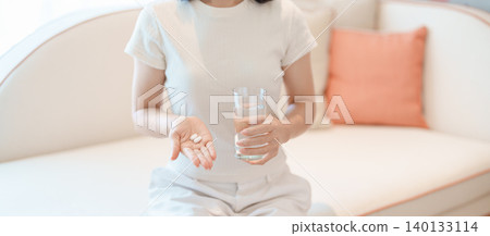 woman hand holding medicine painkiller pill and water glass on the sofa at home, taking for headaches, stomach ache, Diarrhea Pain from food poisoning, Endometriosis, Hysterectomy and Menstrual woman hand holding medicine painkiller pill and water glass on the sofa at home, taking for headaches, stomach ache, Diarrhea Pain from food poisoning, Endometriosis, Hysterectomy and Menstrual 140133114