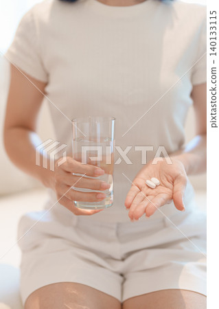 woman hand holding medicine painkiller pill and water glass on the sofa at home, taking for headaches, stomach ache, Diarrhea Pain from food poisoning, Endometriosis, Hysterectomy and Menstrual woman hand holding medicine painkiller pill and water glass on the sofa at home, taking for headaches, stomach ache, Diarrhea Pain from food poisoning, Endometriosis, Hysterectomy and Menstrual 140133115