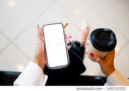 Close up of woman's long nail hands holding white screen phone while sitting indoors over tile floor Close up of woman's long nail hands holding white screen phone while sitting indoors over tile floor 140133325